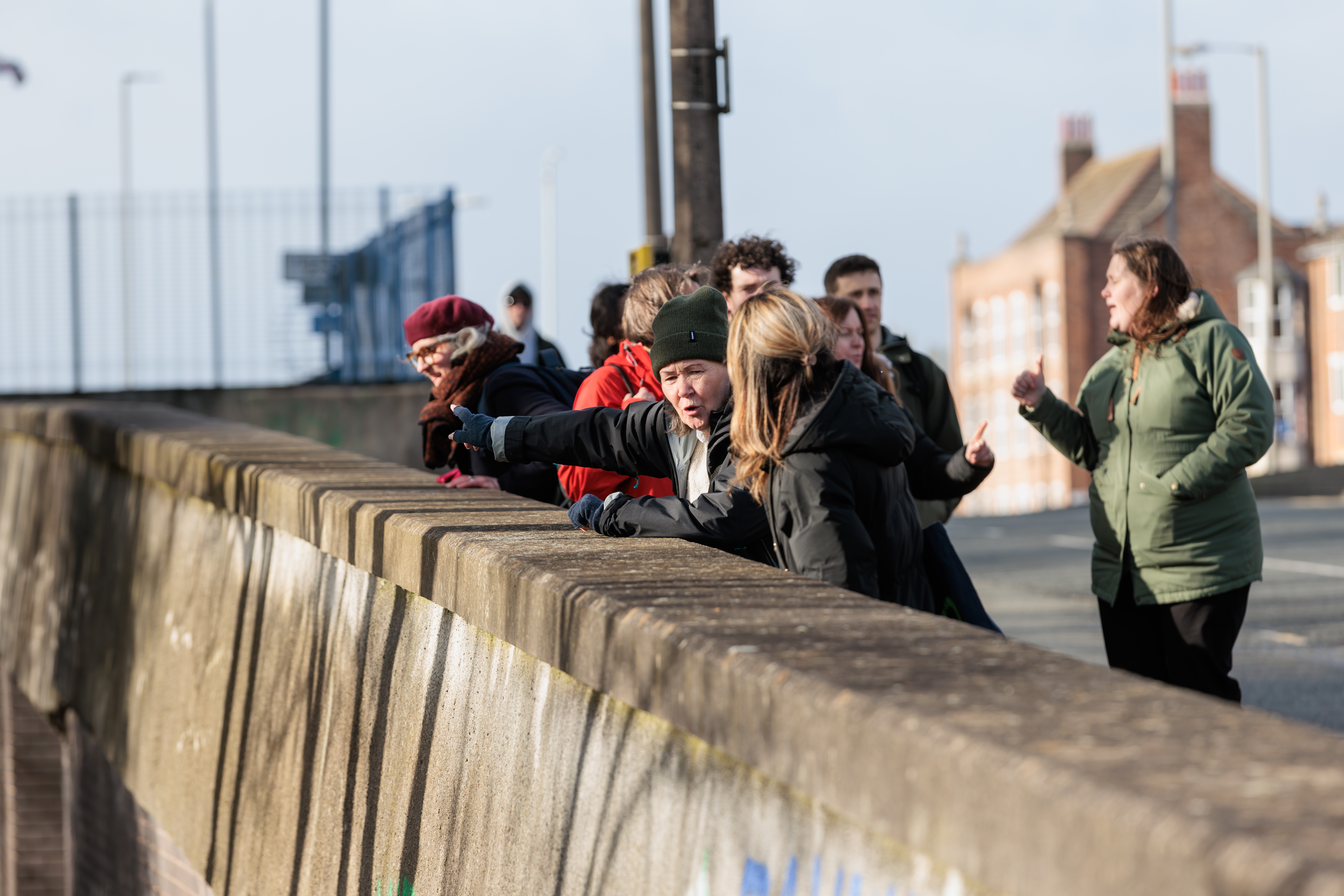 A group of pedestrians look out across a concrete bridge during a guided walk