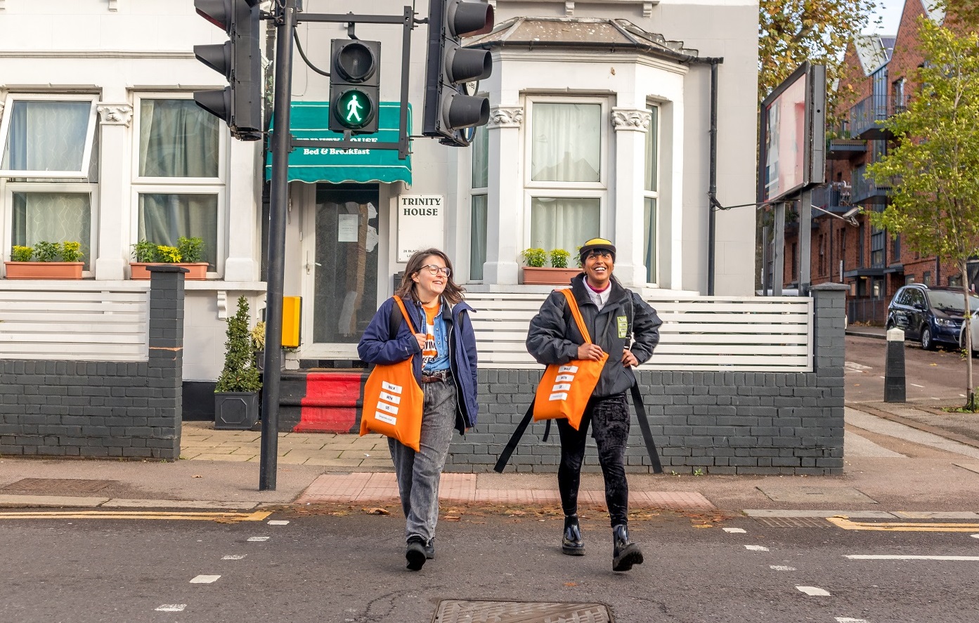 Two people crossing a signalised crossing, which is showing the 'green man'